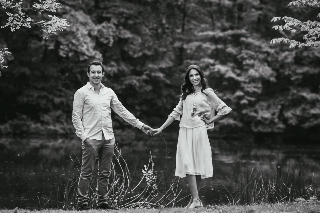 Black-and-white engagement portrait of a couple holding hands outdoors