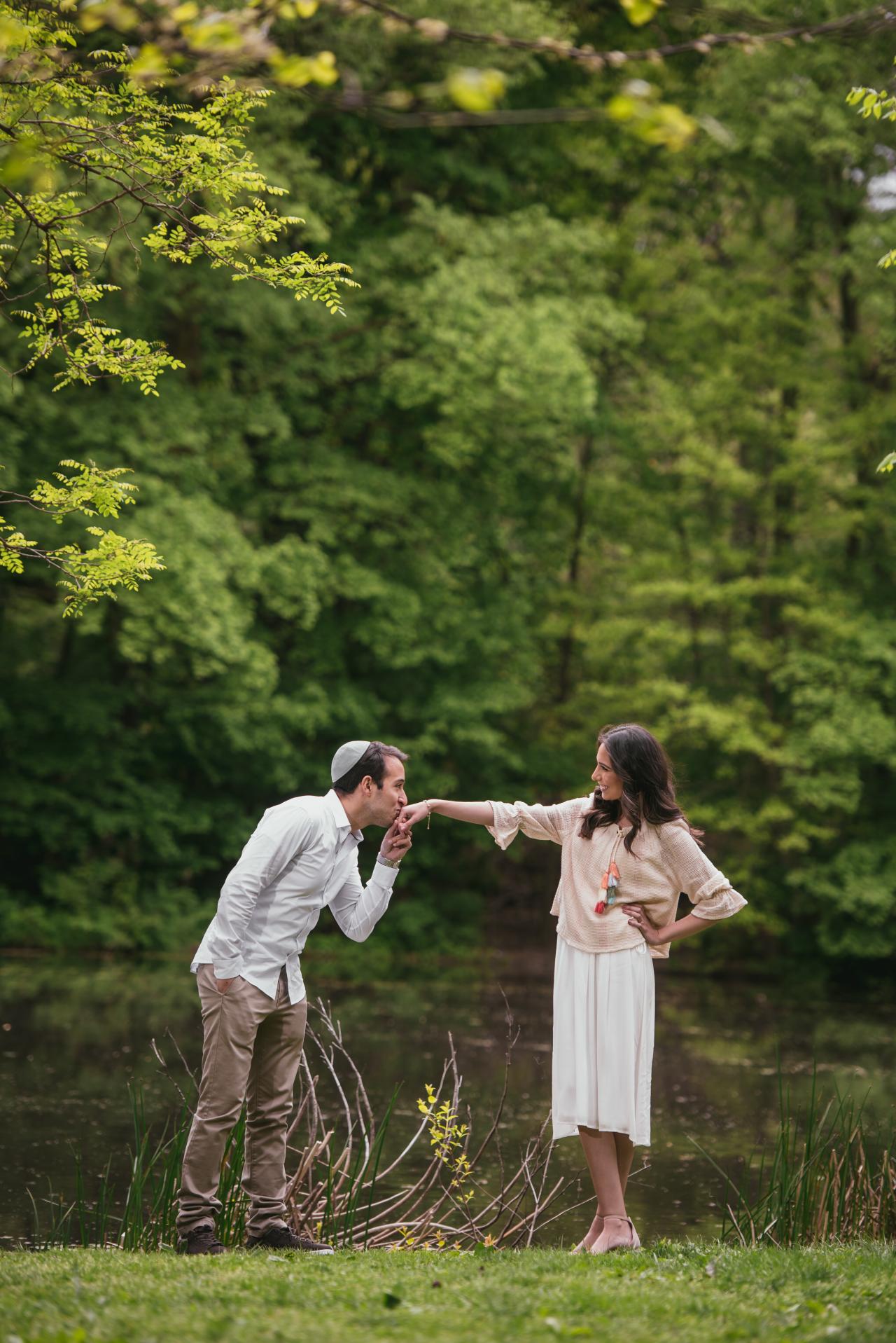 Man kissing his partner’s hand beside the water