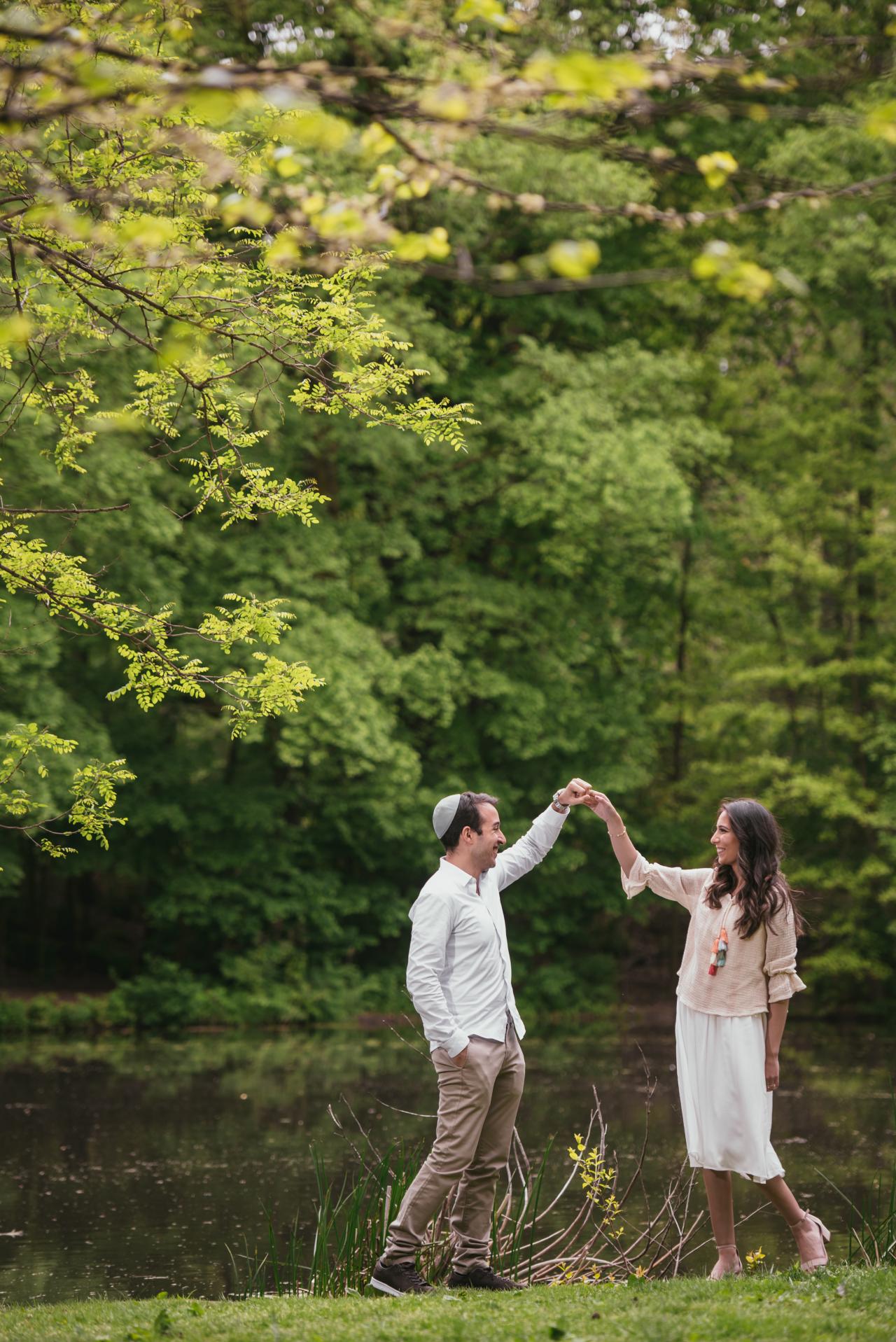 Couple twirling together beneath leafy branches