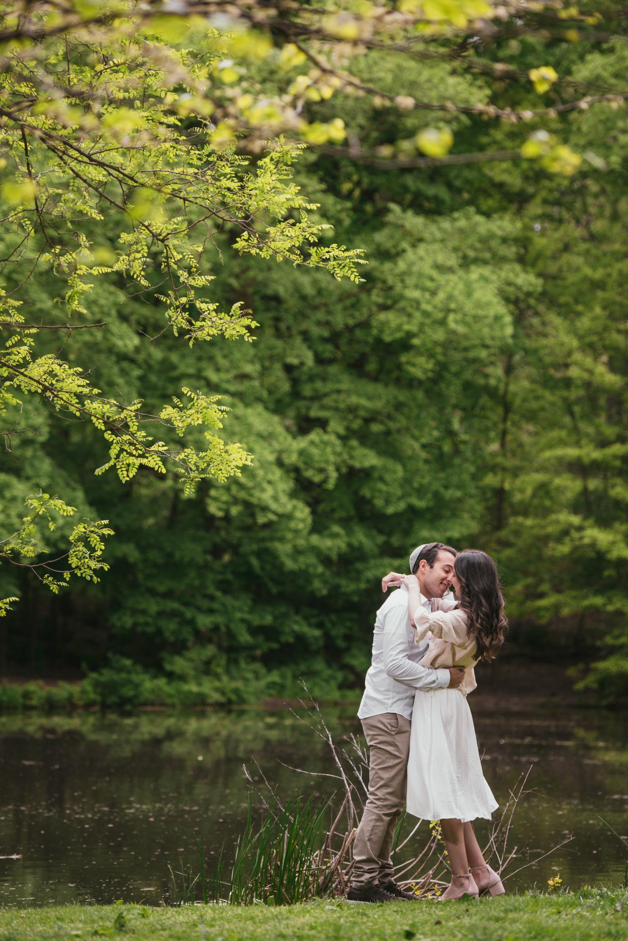 Couple embracing beside a shaded pond