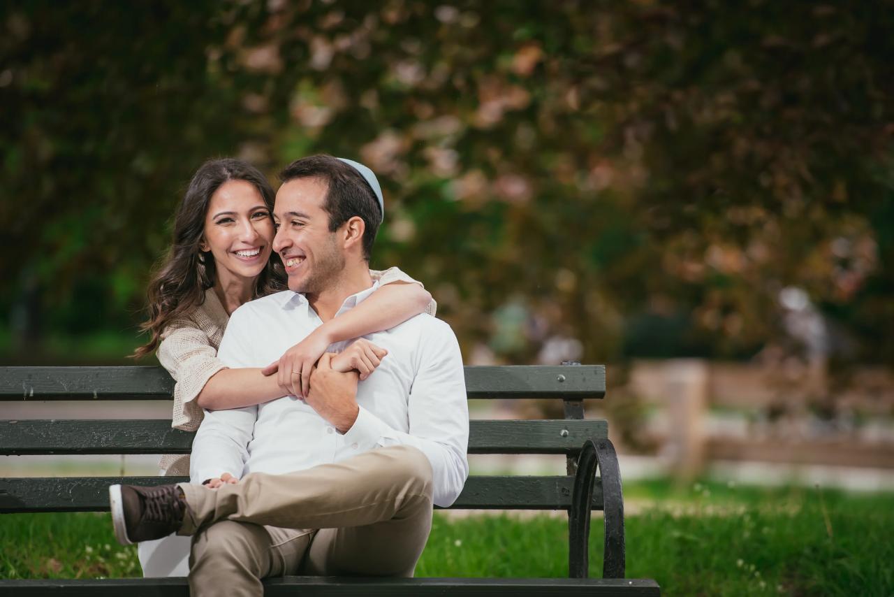 Couple smiling together while seated on a park bench