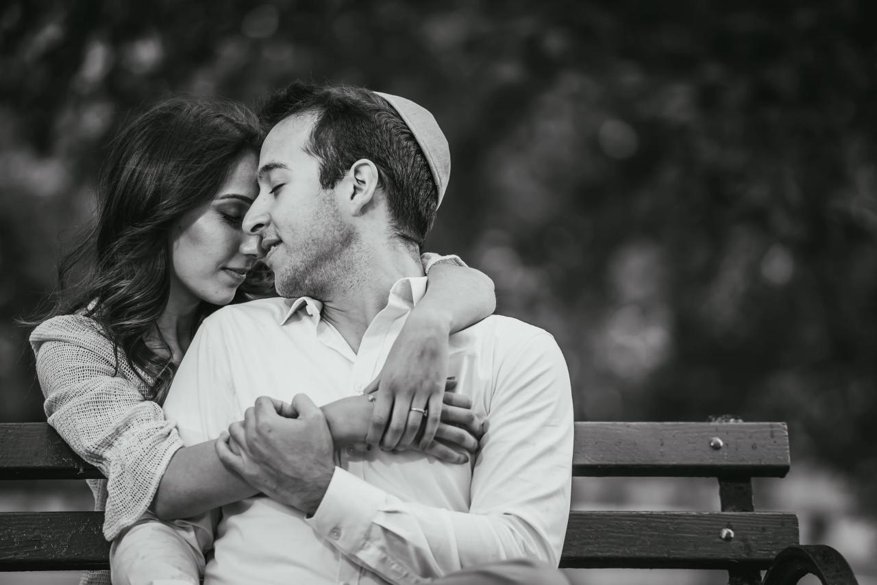 Black-and-white portrait of a couple embracing on a bench