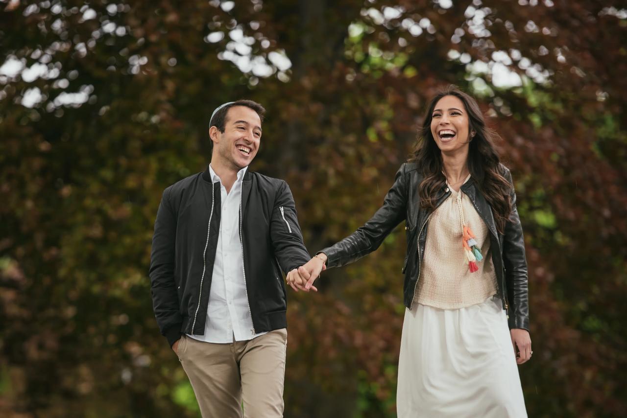 Couple laughing together beneath park trees