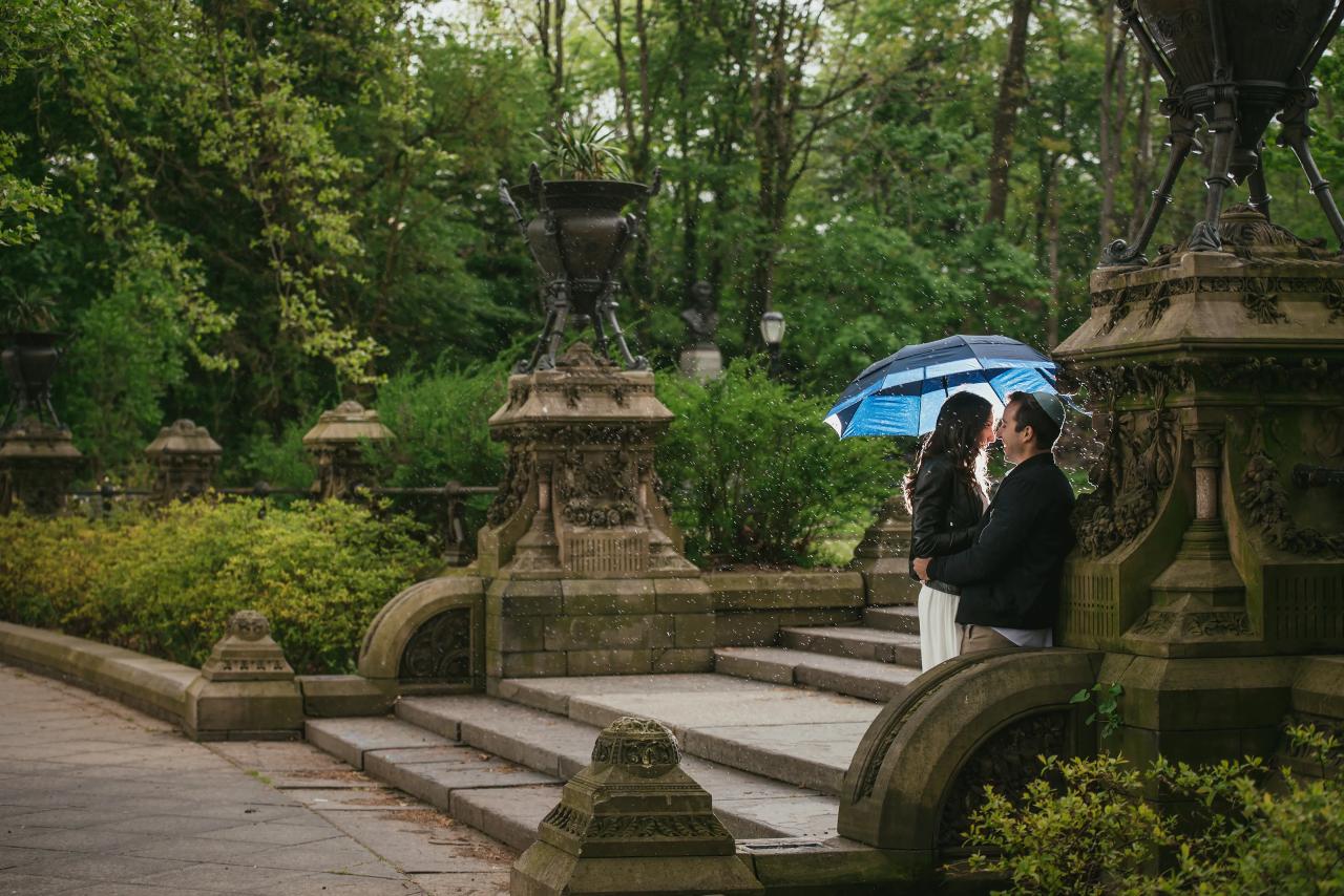 Couple beneath a blue umbrella beside ornate stone steps