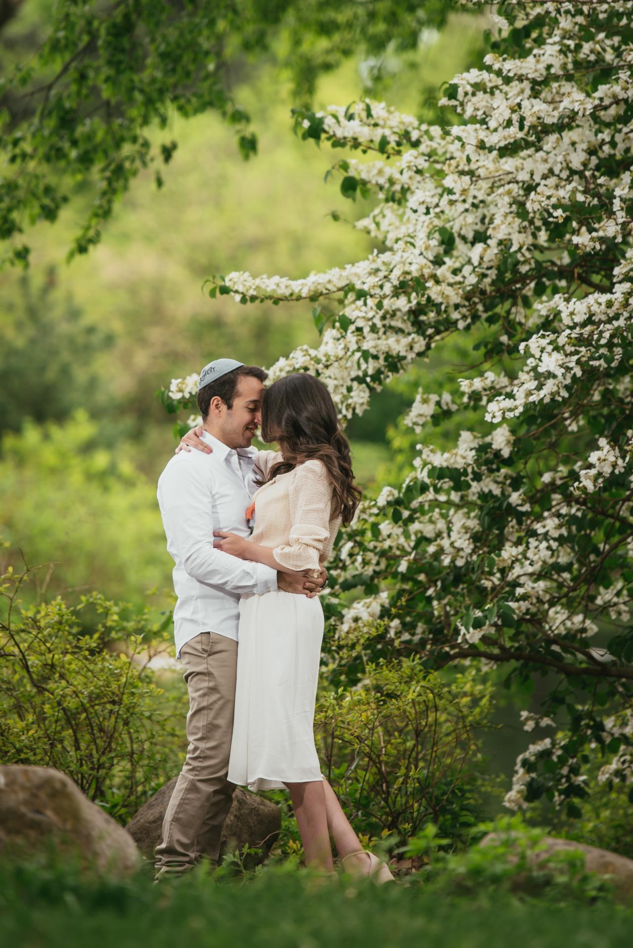 Full-length engagement portrait among white spring blossoms