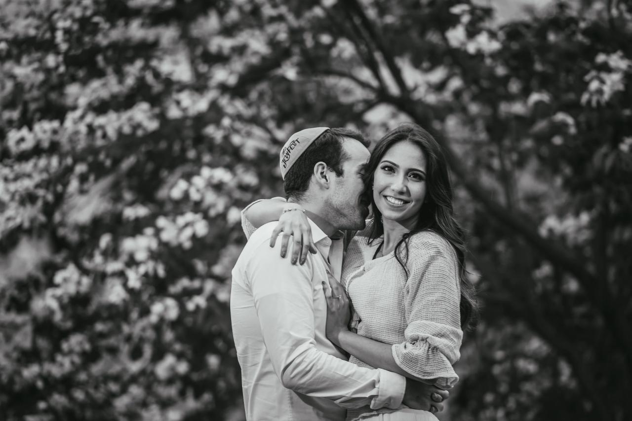 Black-and-white close engagement portrait beneath blossoms