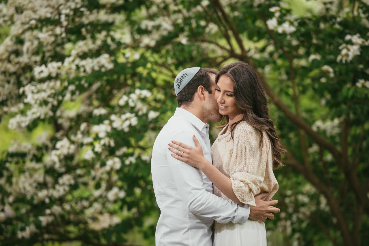 Couple touching foreheads in front of white flowers