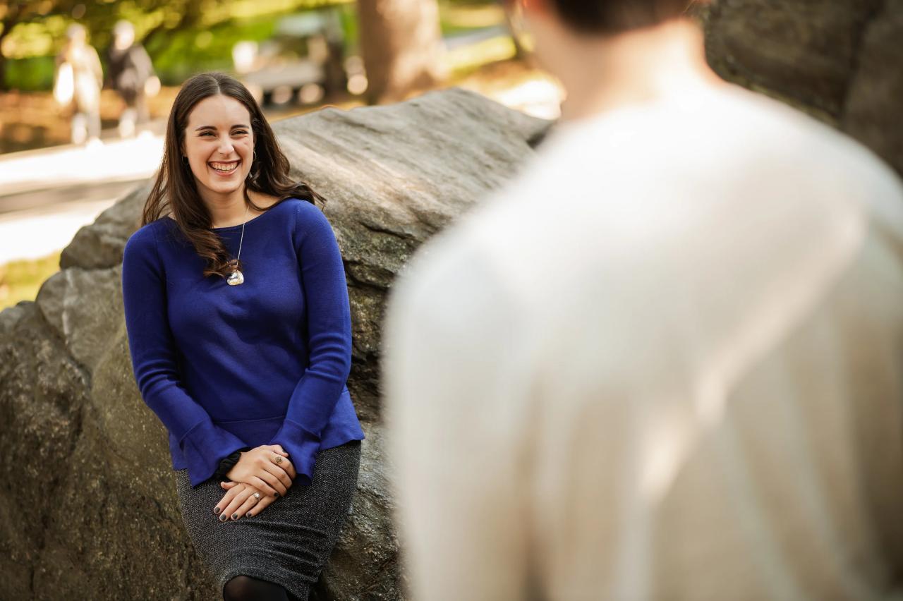 Woman smiling toward her partner while seated beside a rock