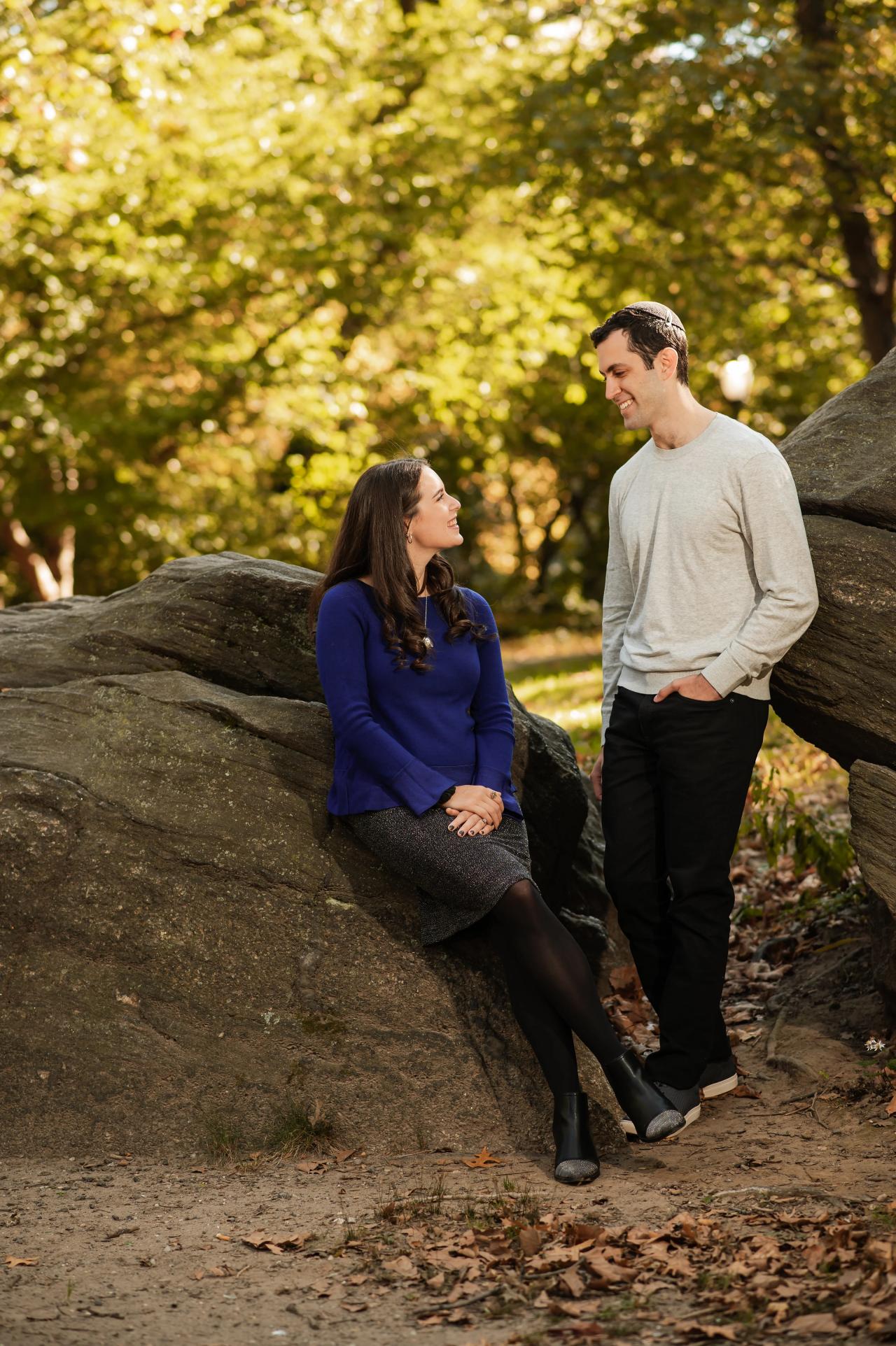 Couple sharing a quiet moment beside a sunlit boulder