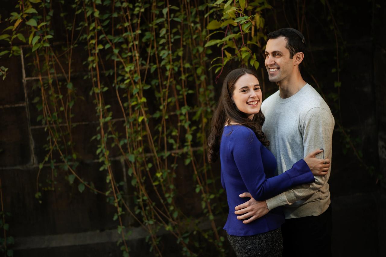 Couple embracing beside a wall covered with trailing greenery