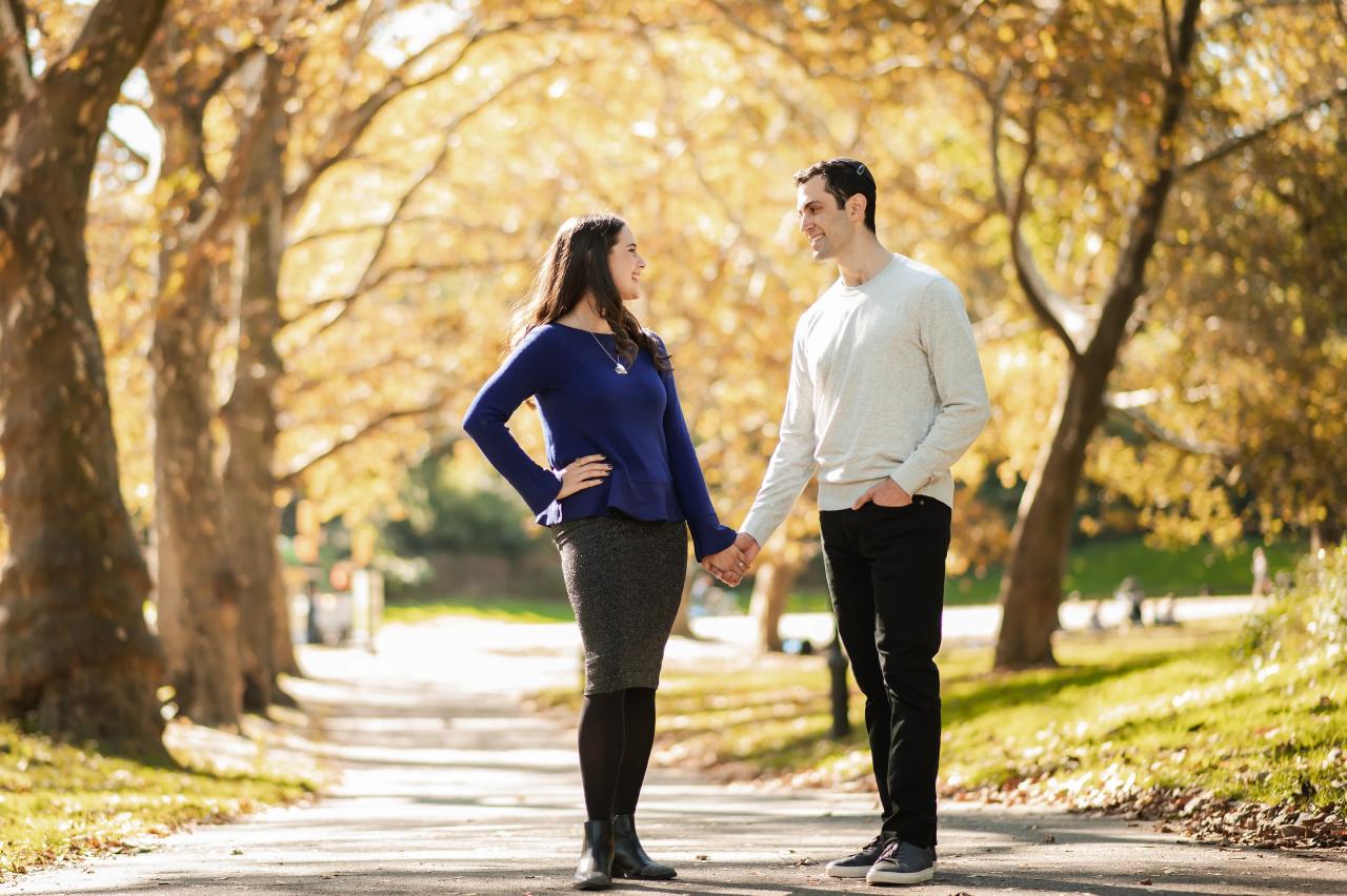 Couple holding hands and smiling at each other on a park path