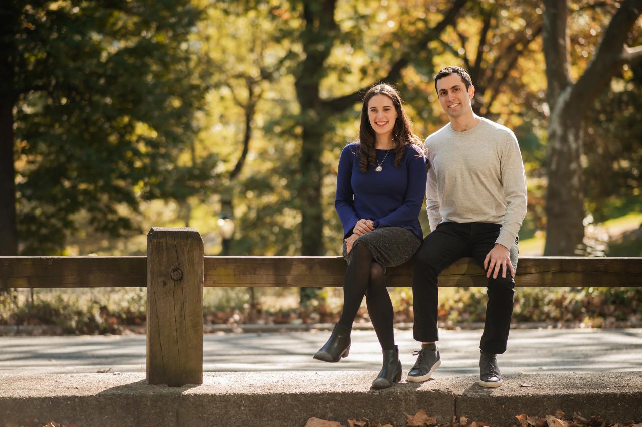 Couple sitting together on a wooden park railing