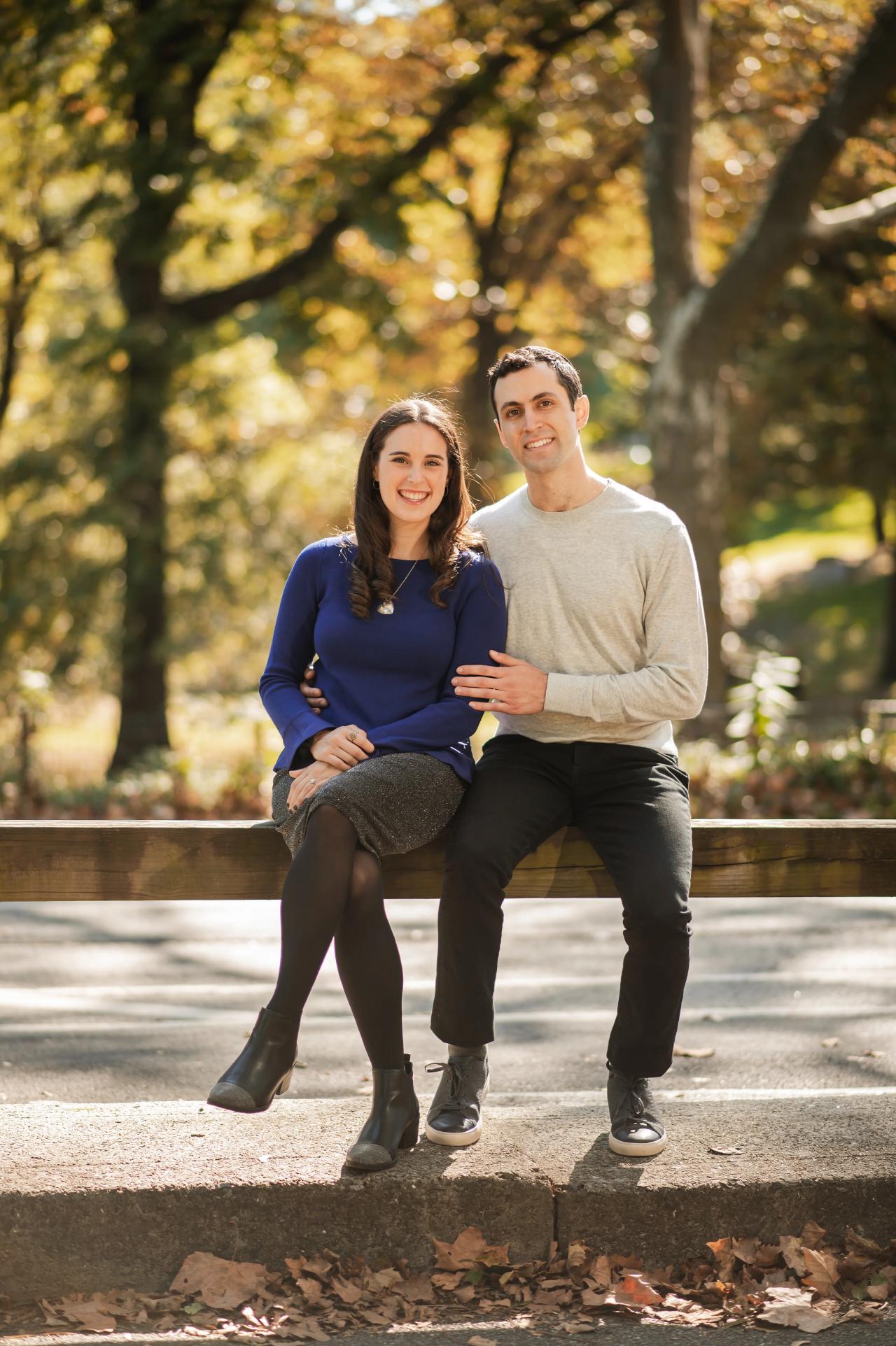 Couple laughing while seated beneath autumn trees