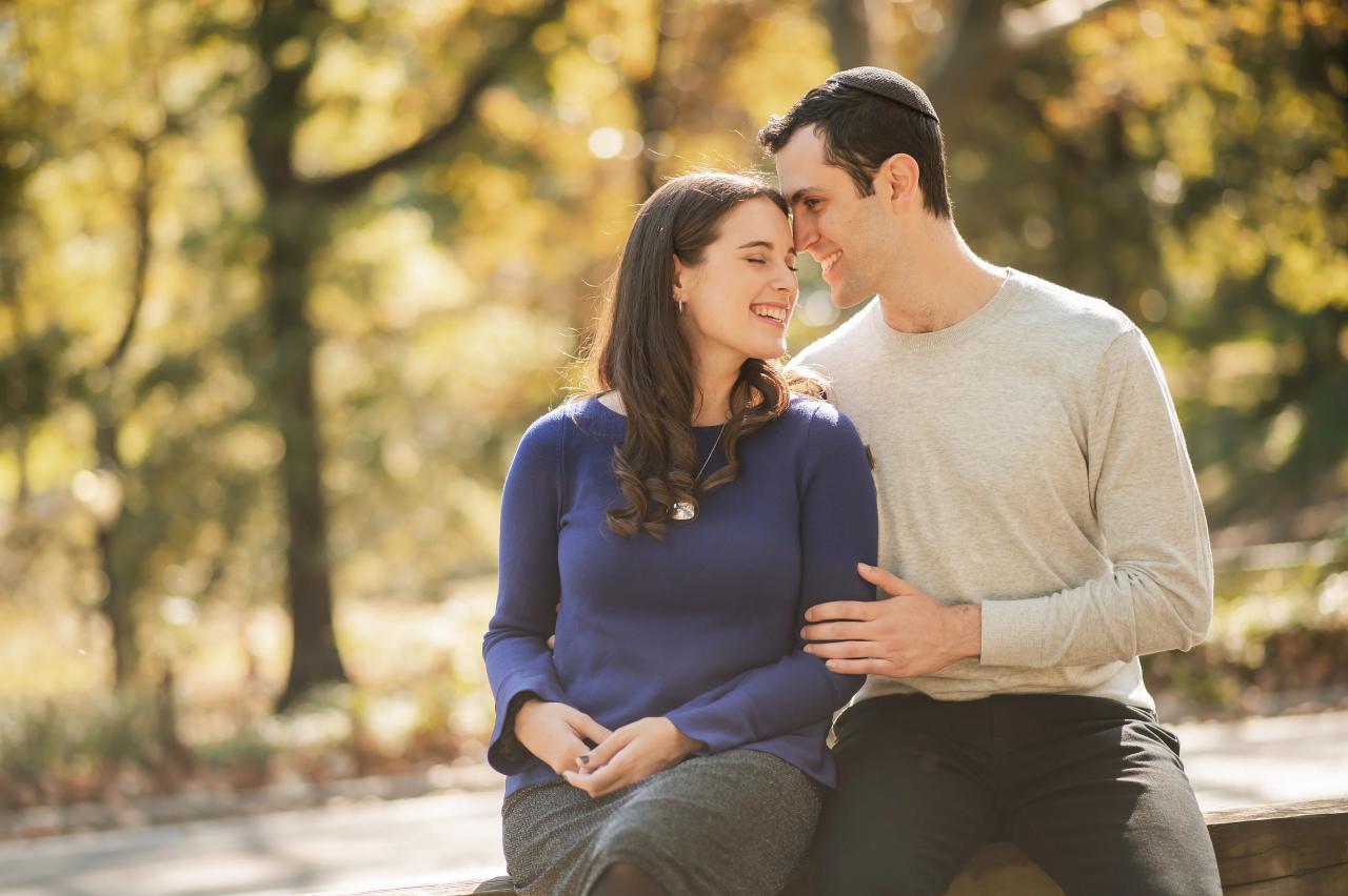 Man kissing his partner’s forehead in warm park light