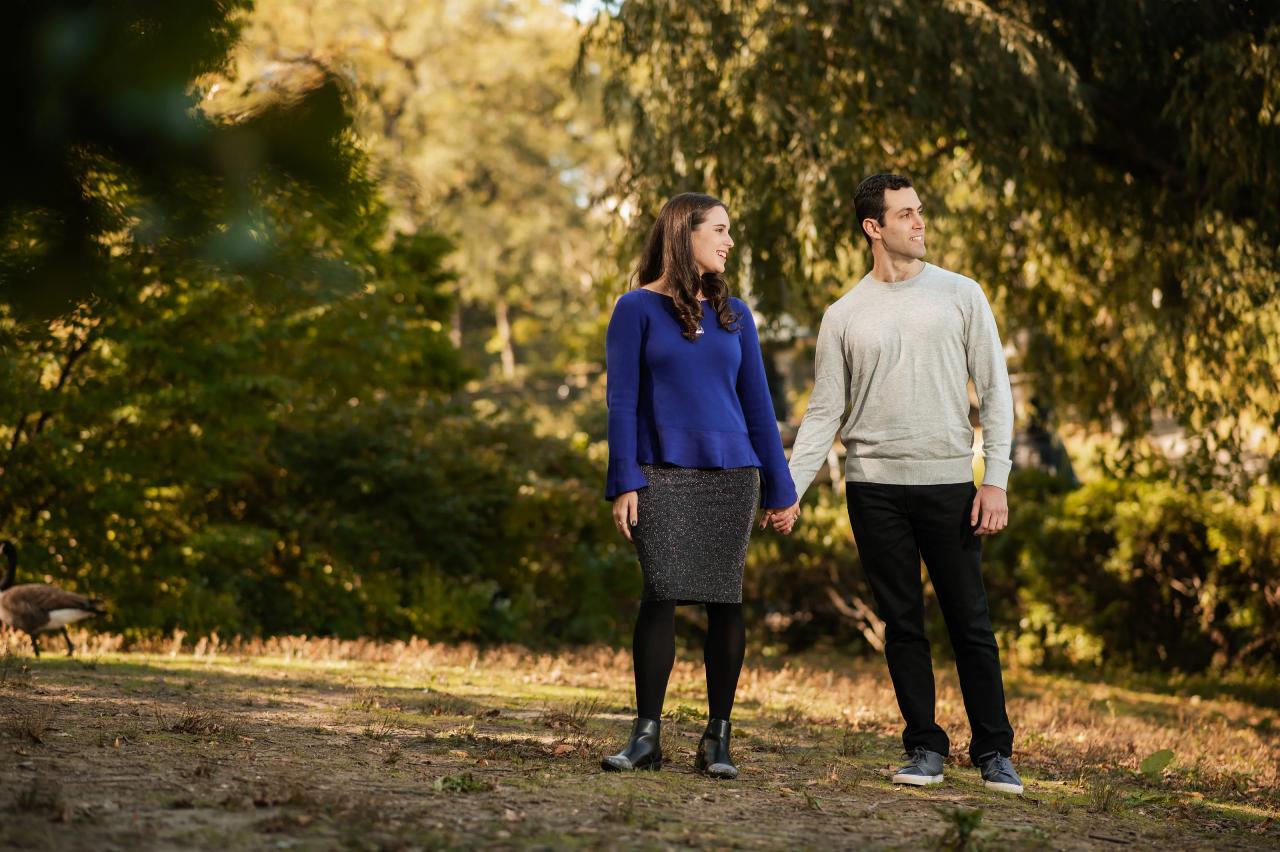 Couple holding hands beside autumn foliage