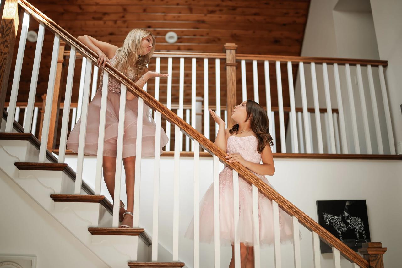 Twin sisters looking toward each other on a wooden staircase