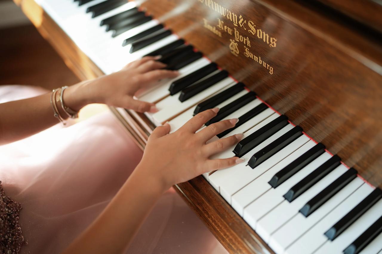 Close view of hands playing the keys of a grand piano