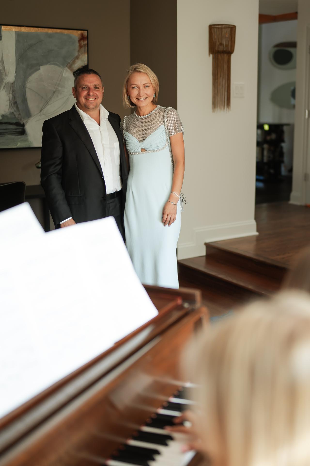 Two guests smiling together beside a grand piano
