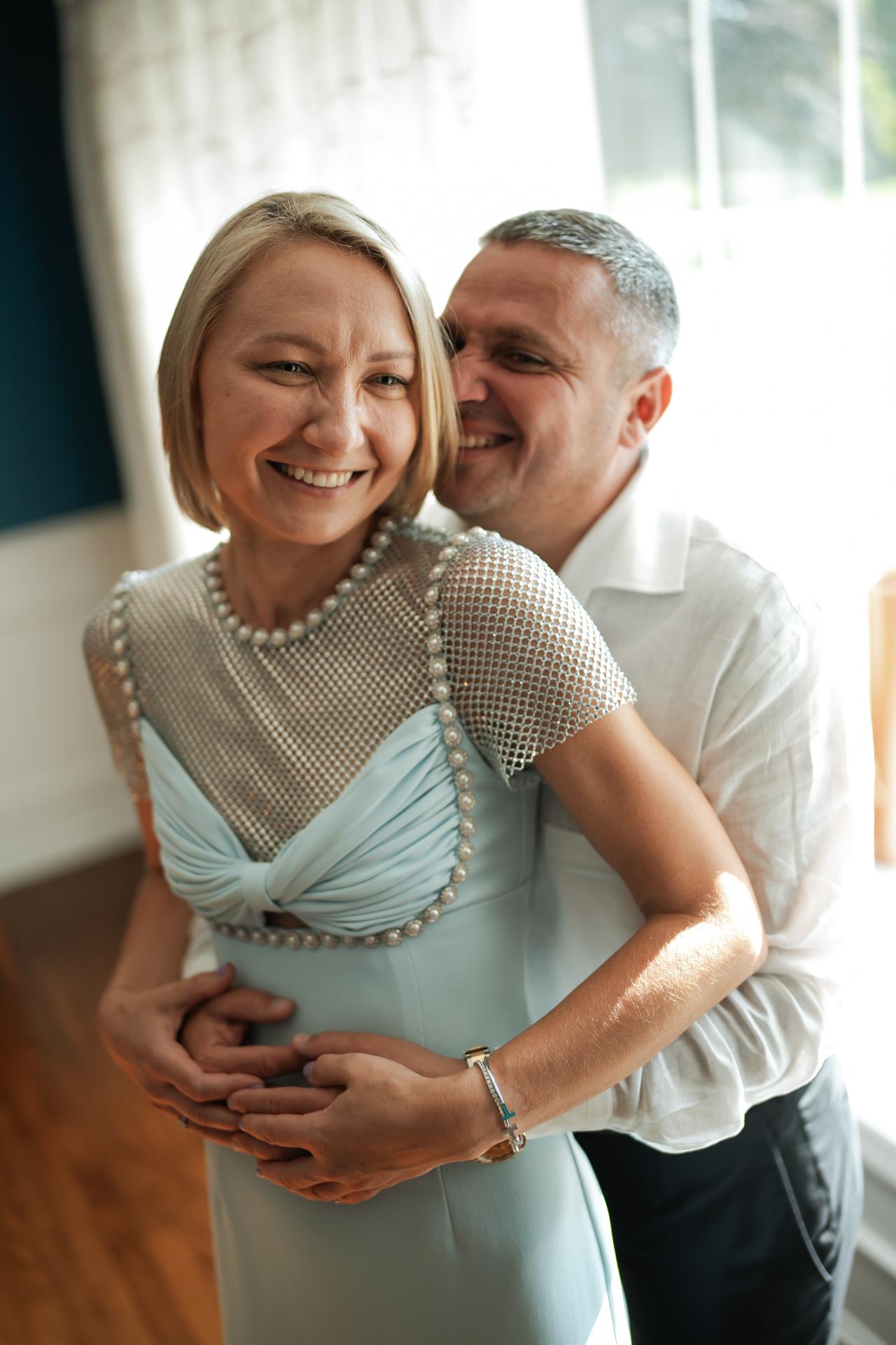 Two family members sharing an embrace beside a sunlit window