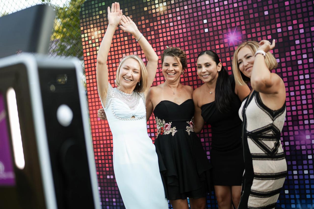 Friends celebrating together in front of a colorful photo backdrop