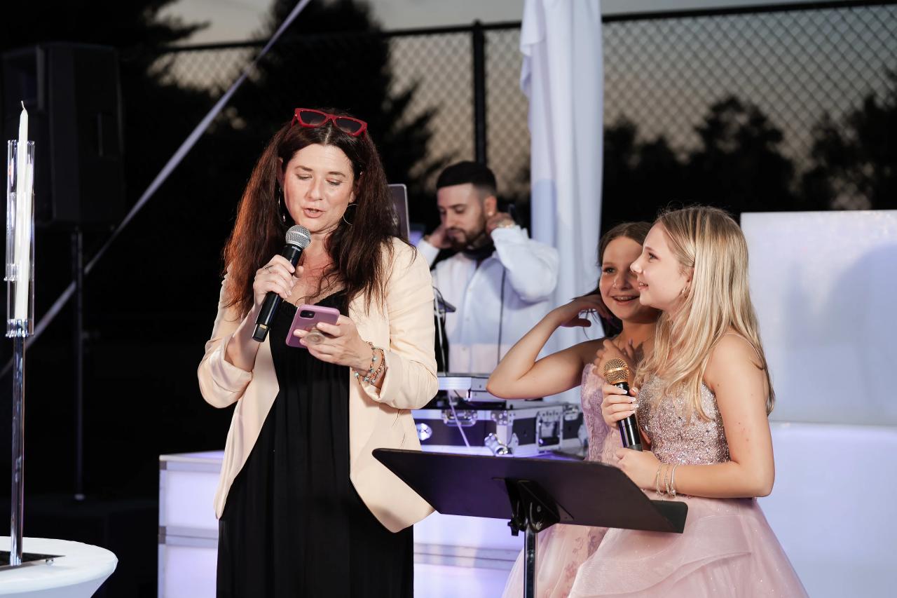 A guest speaking into a microphone with the sisters beside her