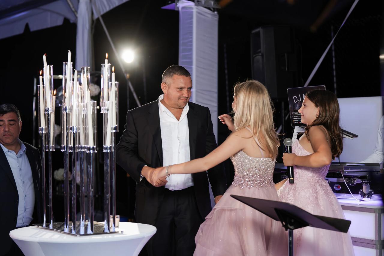A sister dancing with a family member beside the reception candle display