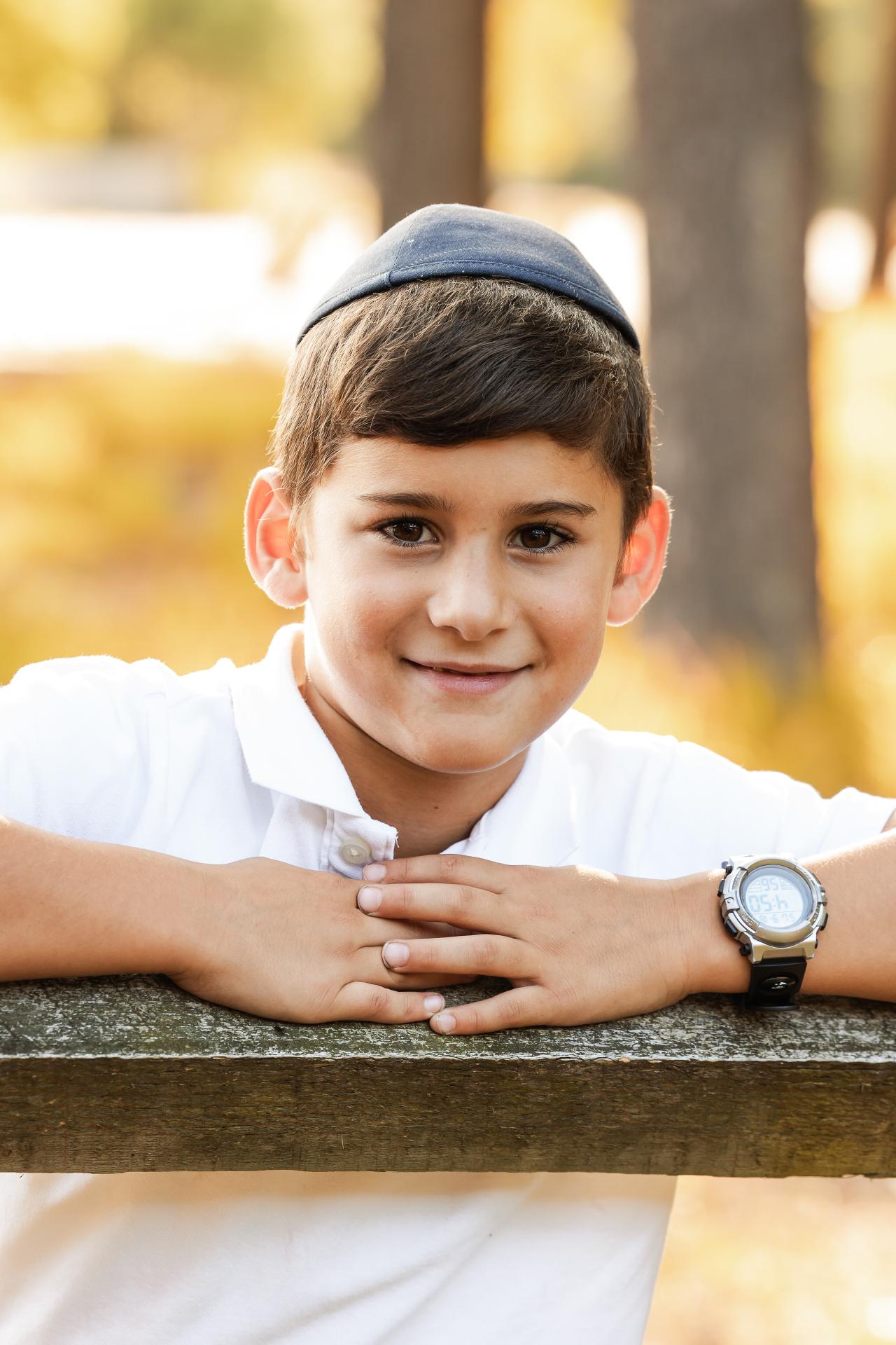 Boy resting his chin on his hands at a wooden fence during a family photoshoot