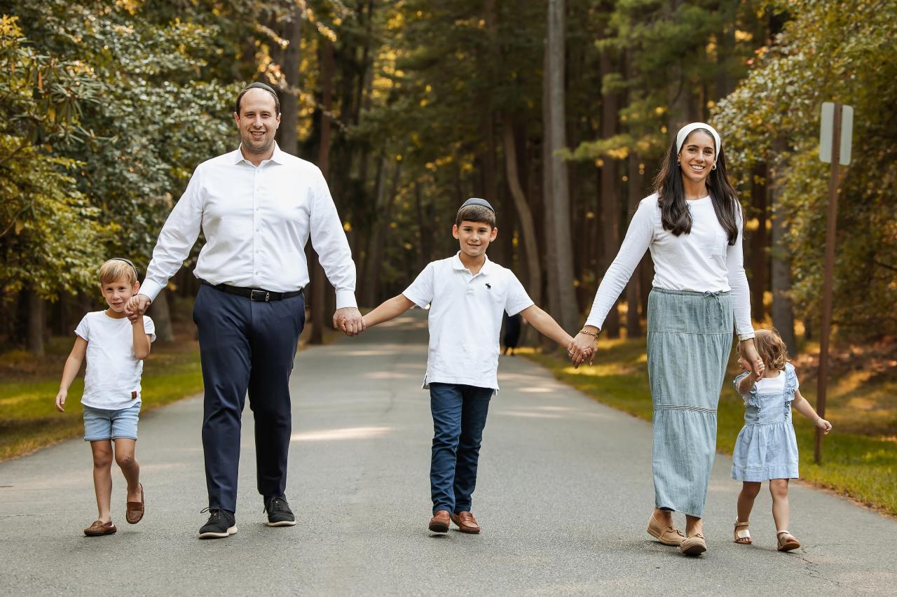 Family of five walking hand in hand along a tree-lined path