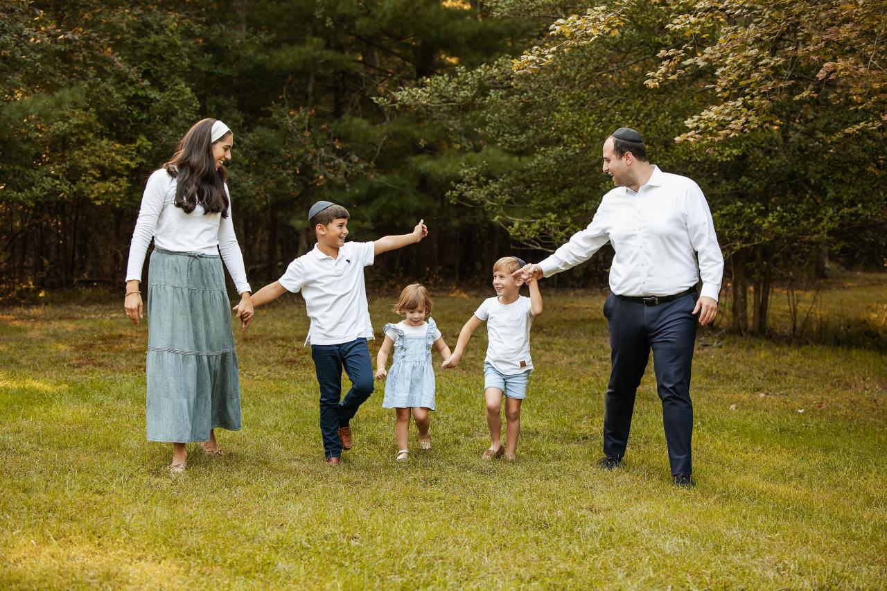 Family holding hands and smiling at one another on the autumn lawn