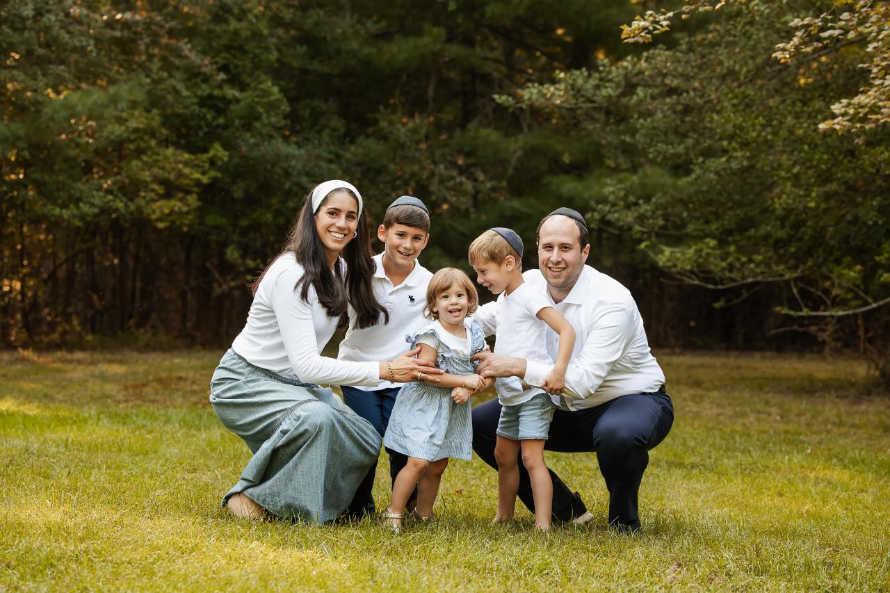 Family kneeling together on the grass for an outdoor portrait