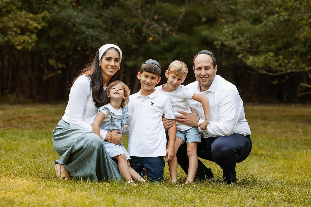 Parents and three children facing the camera together on the lawn