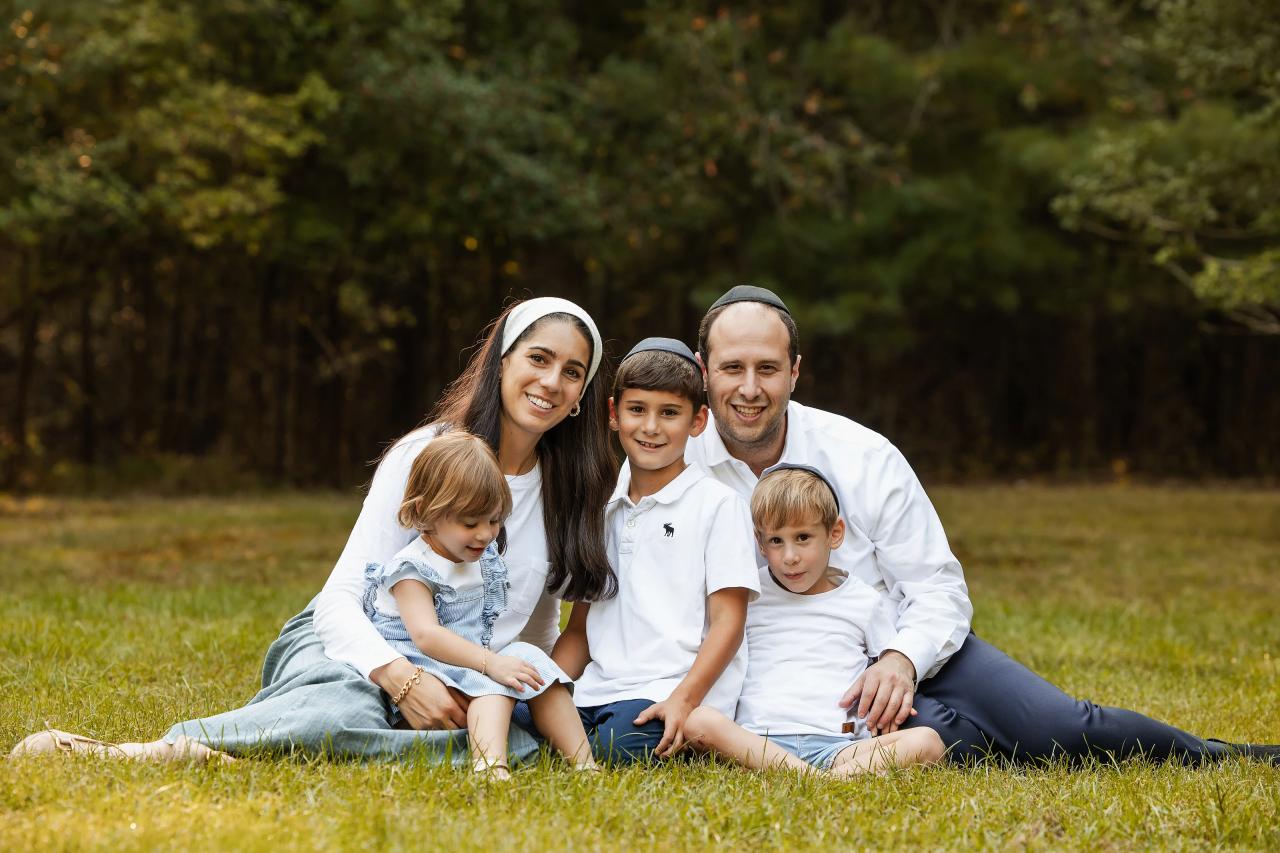 Family seated close together on the grass beneath autumn trees