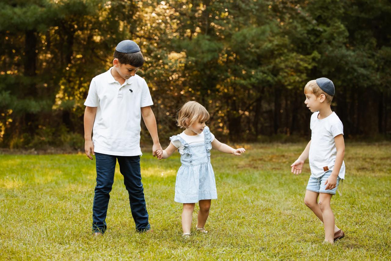 Little girl holding hands with her brothers on the grass