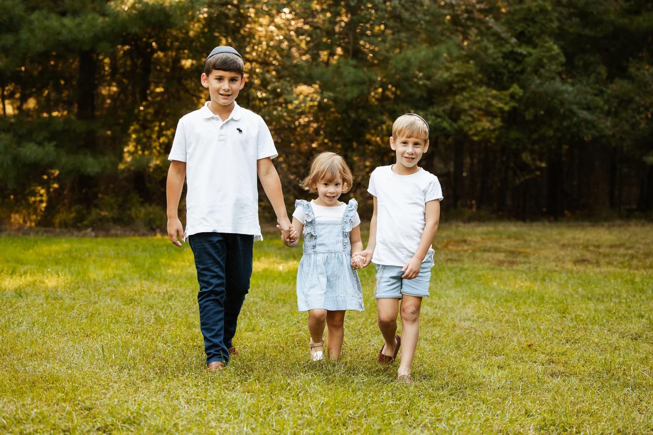 Three children walking hand in hand across the lawn