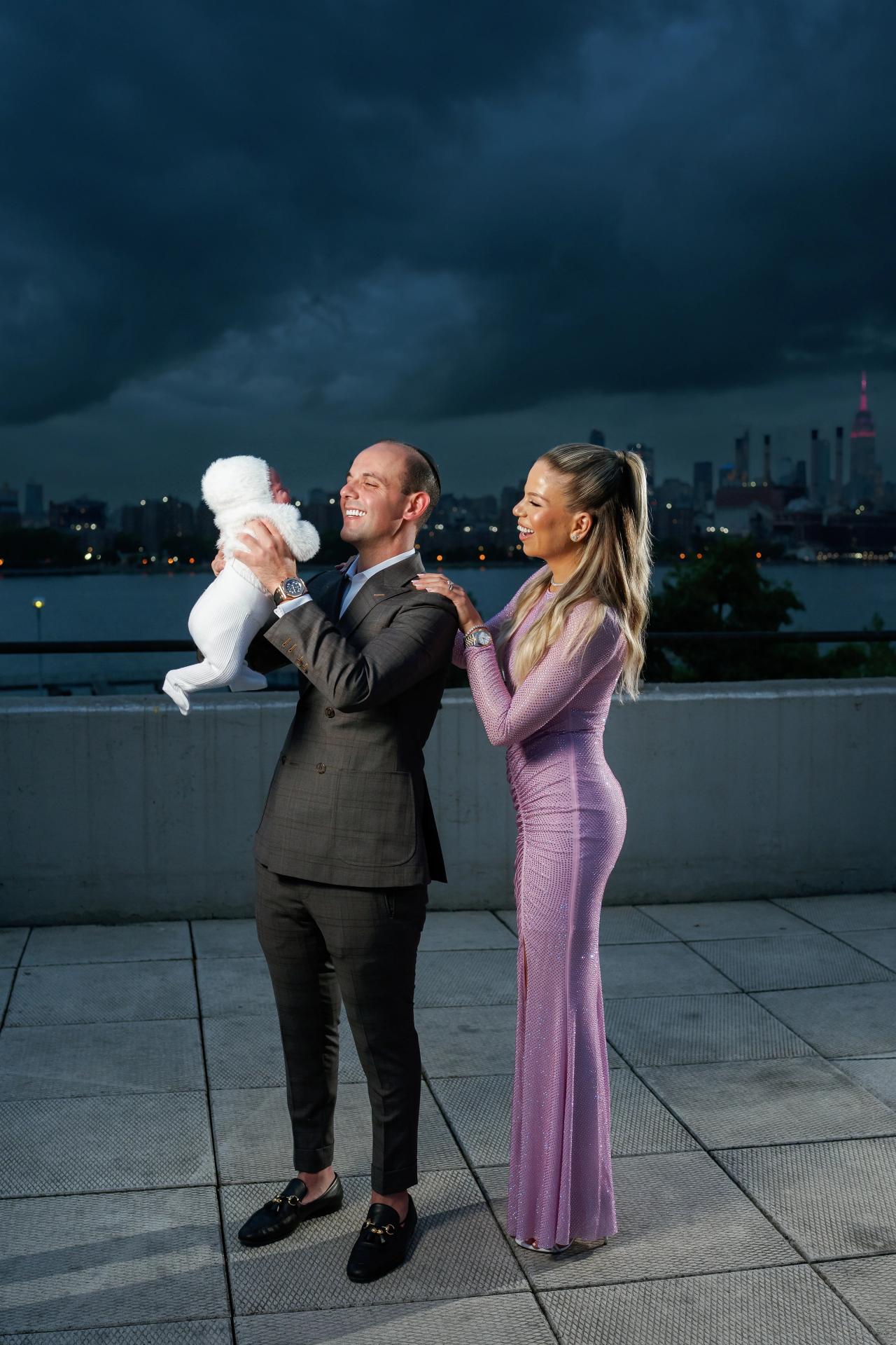 Father lifting his baby as mother smiles beside him
