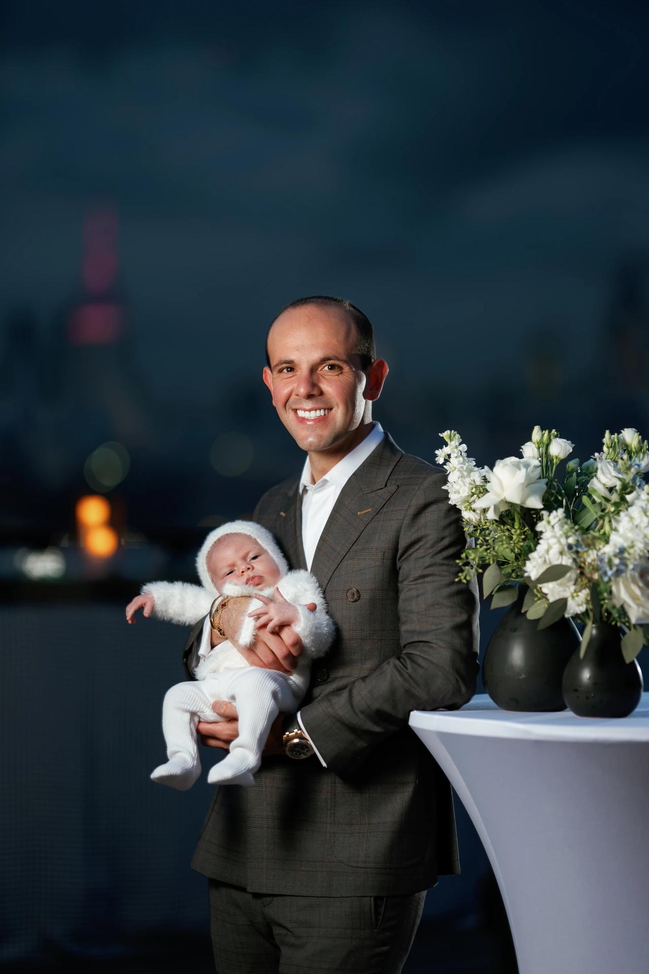 Father smiling while holding his baby during the family celebration