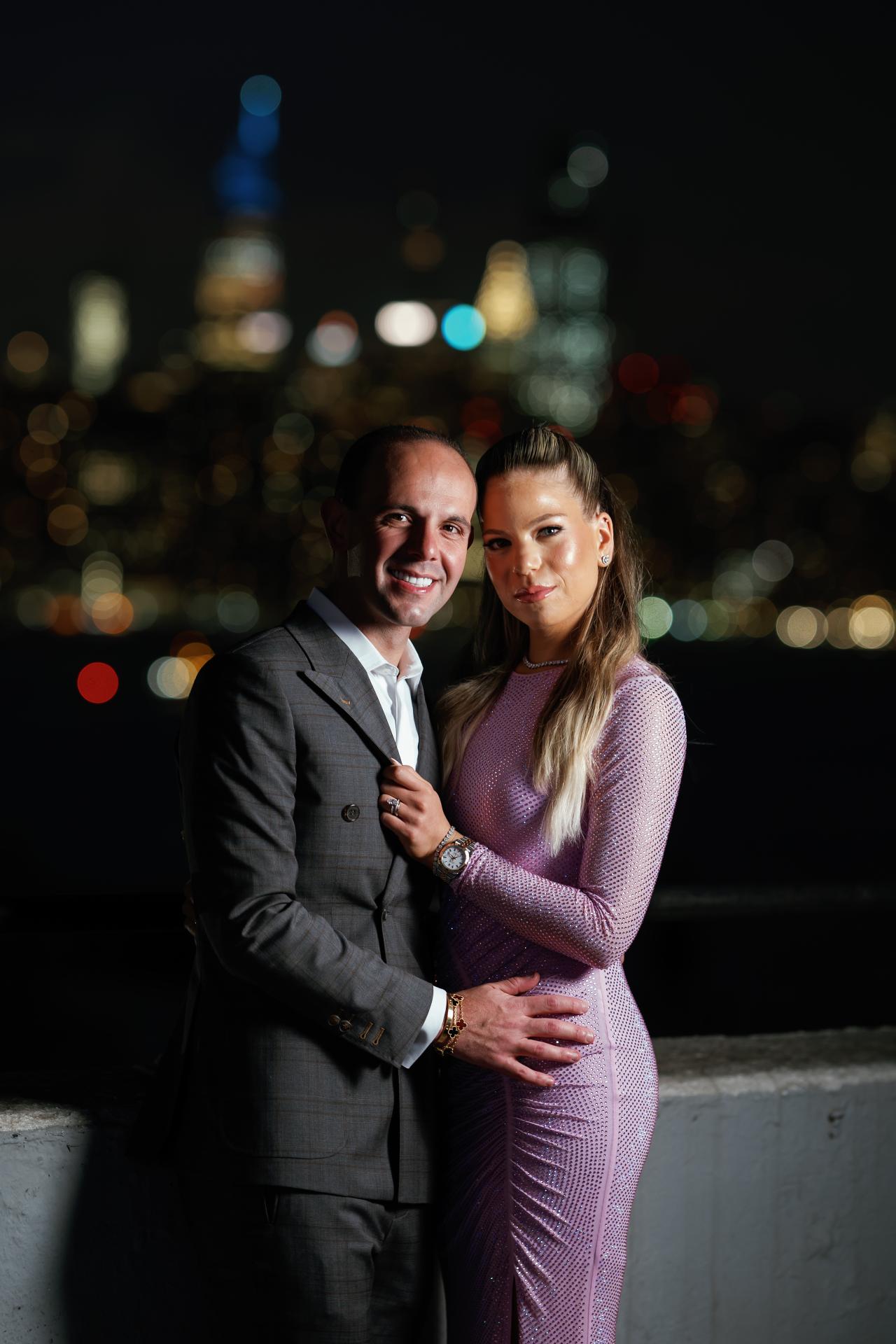 Parents embracing with the illuminated skyline in the background