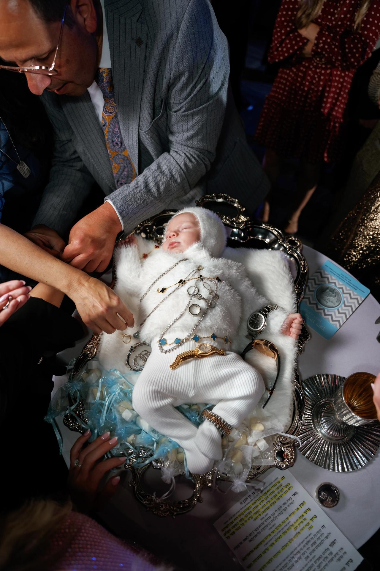 Baby resting on the decorated cushion with silver coins at the ceremony table
