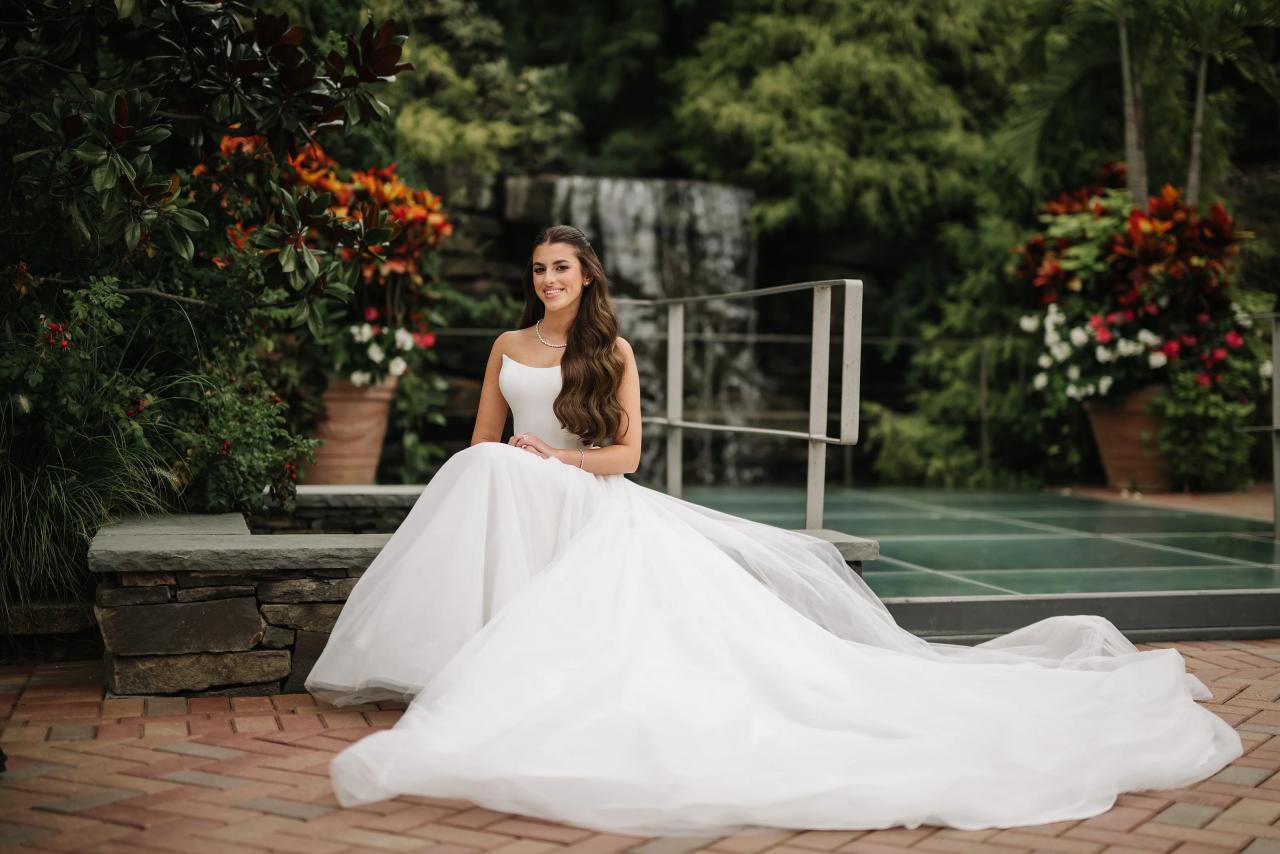 Bride seated beside the garden pool with her dress spread around her. Crest Hollow wedding in Woodbury, Long Island.