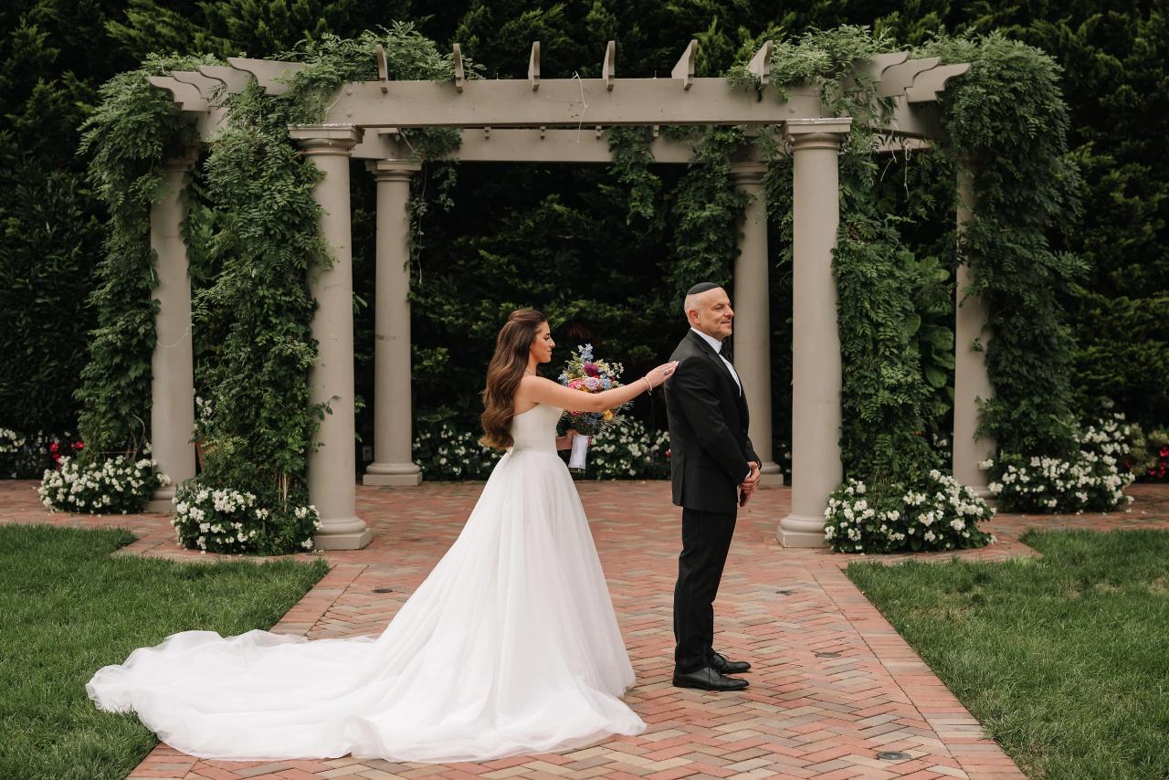 Bride greeting a family member beneath the pergola. Crest Hollow wedding in Woodbury, Long Island.