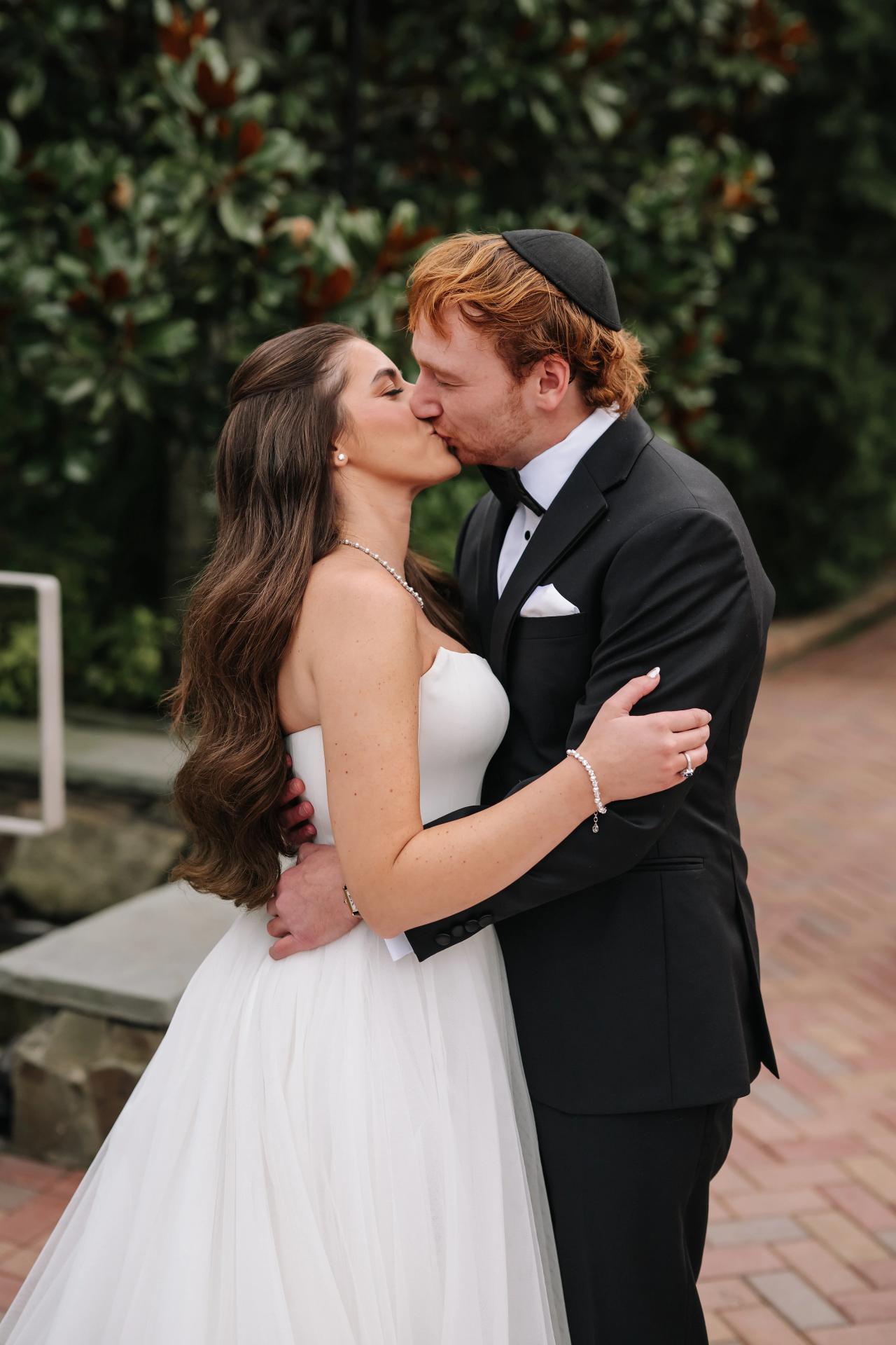 Bride and groom sharing a kiss beside the garden pool. Crest Hollow wedding in Woodbury, Long Island.
