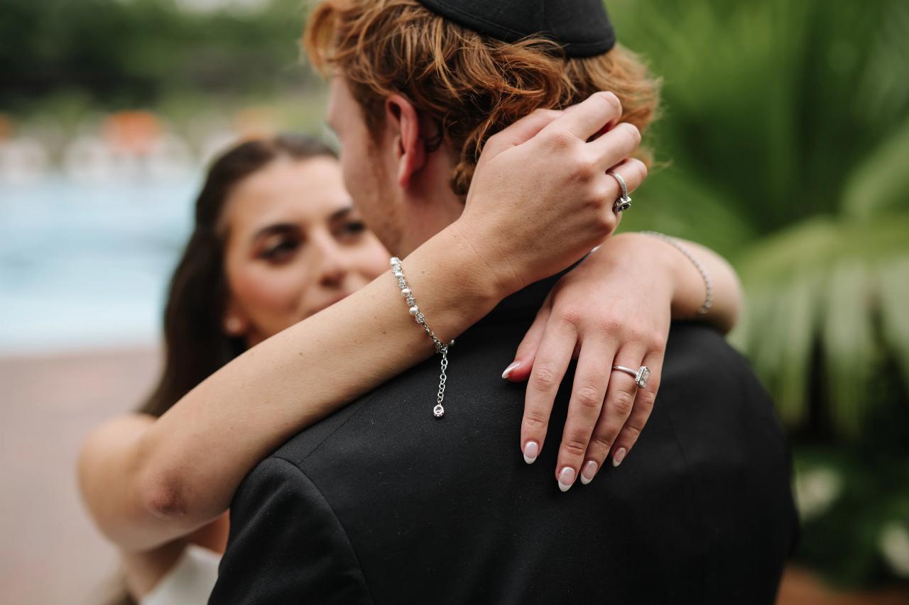 Bride embracing the groom beside tropical palms. Crest Hollow wedding in Woodbury, Long Island.