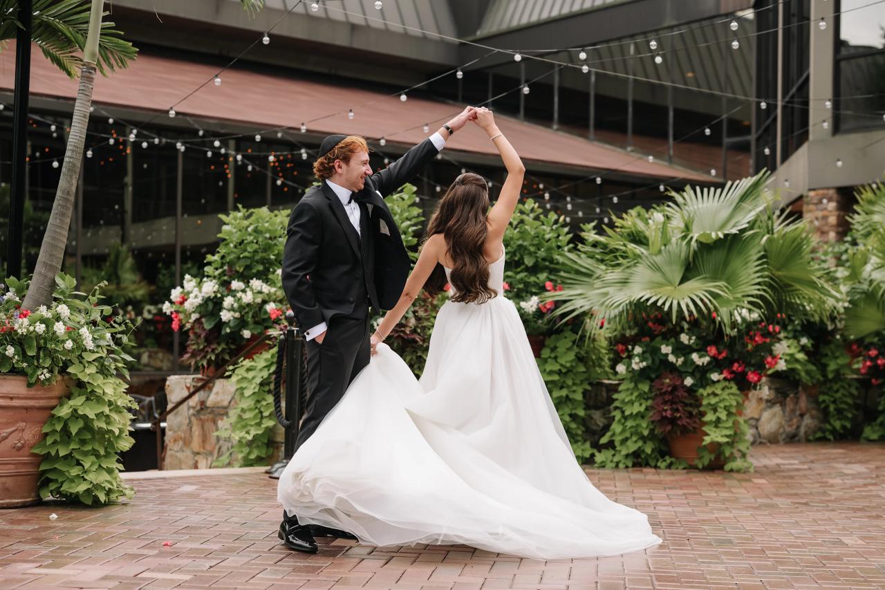 Groom twirling the bride on a brick garden path. Crest Hollow wedding in Woodbury, Long Island.