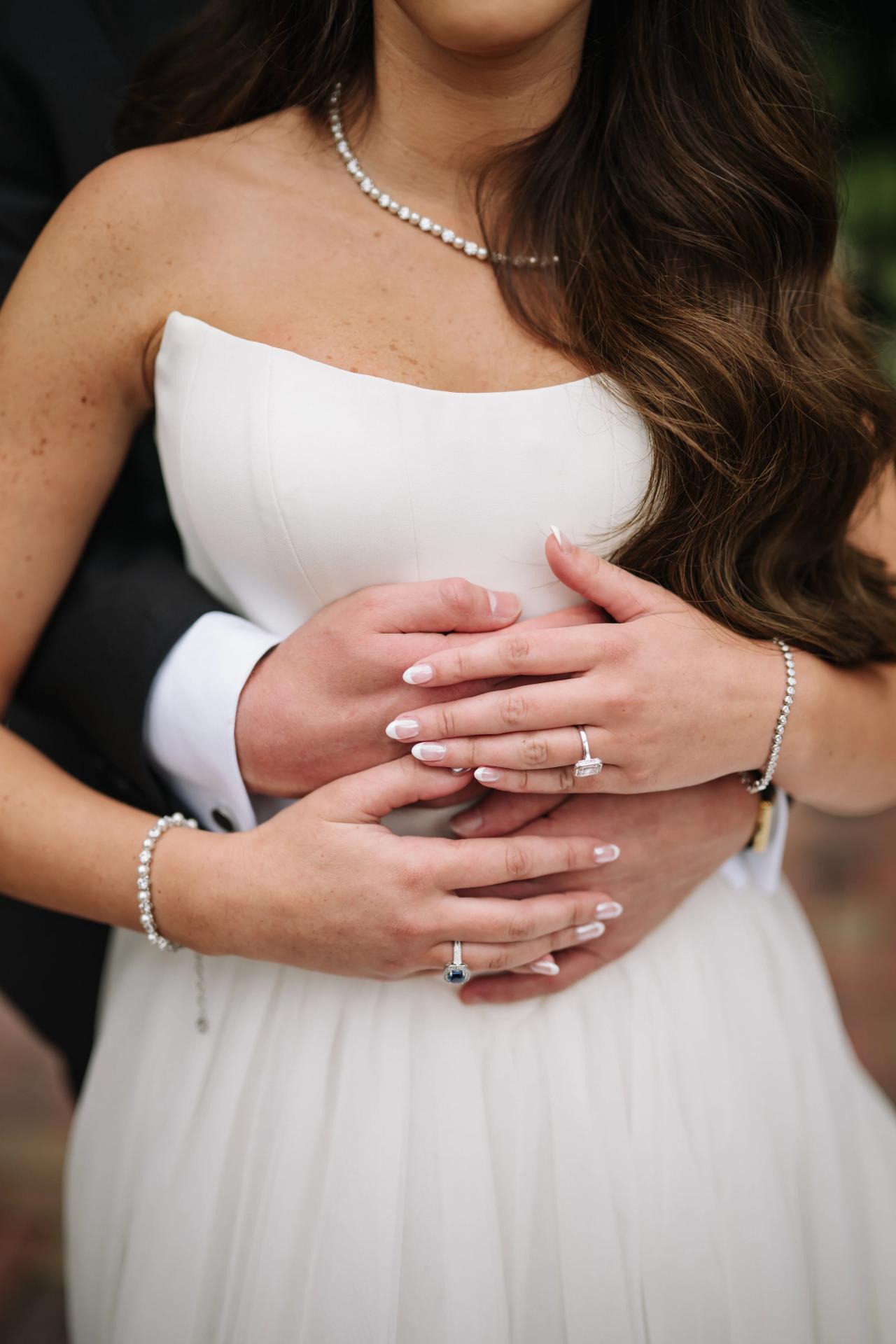 Wedding rings and hands against the bridal dress. Crest Hollow wedding in Woodbury, Long Island.