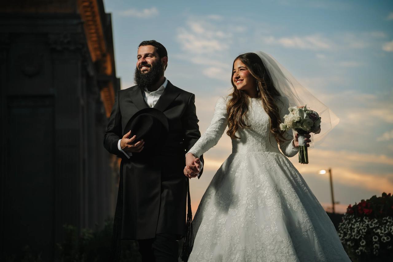Bride and groom holding hands against the Detroit sunset
