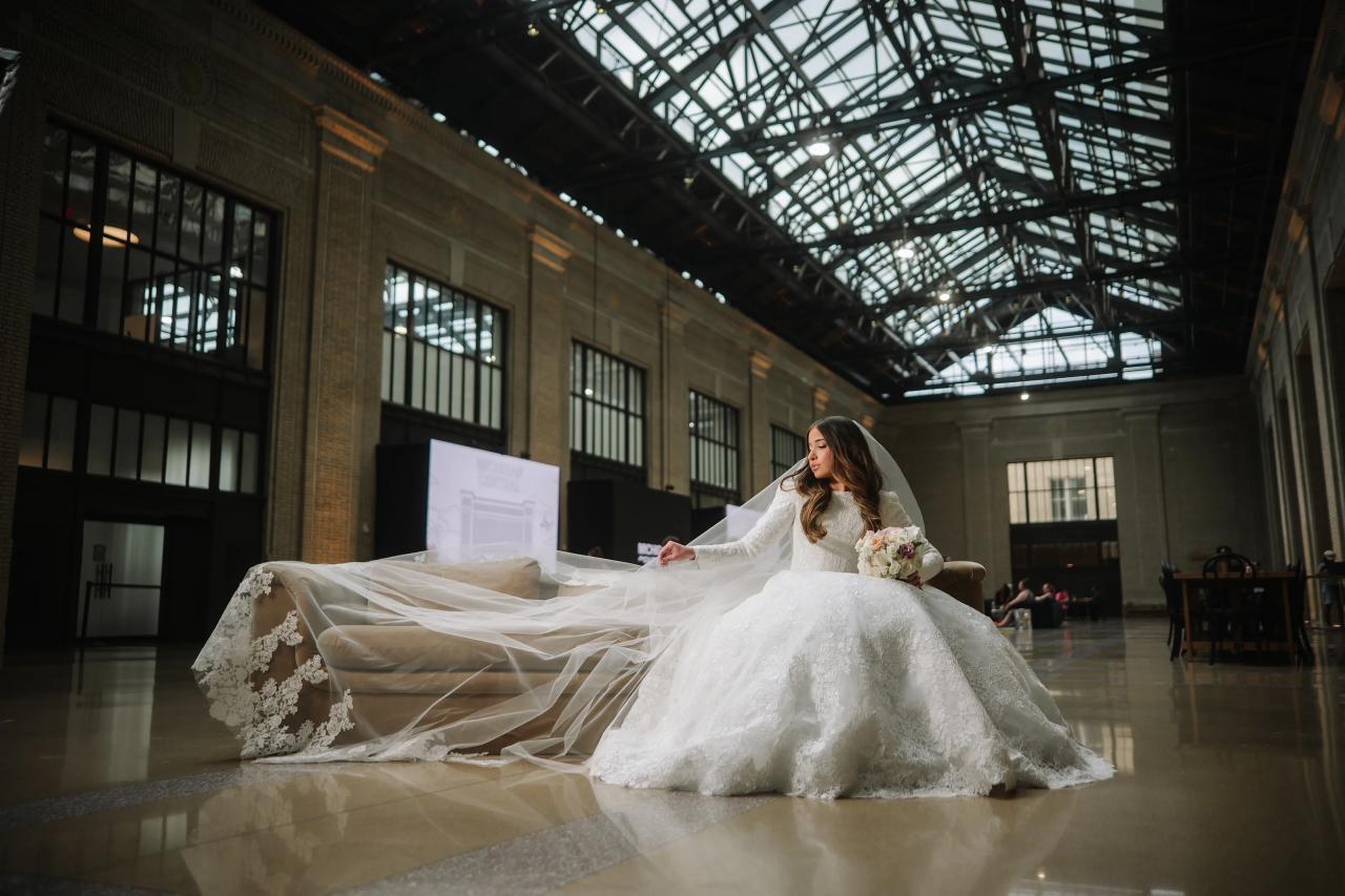 Bride seated beneath the dramatic glass ceiling of a grand hall. Jewish wedding in Detroit.