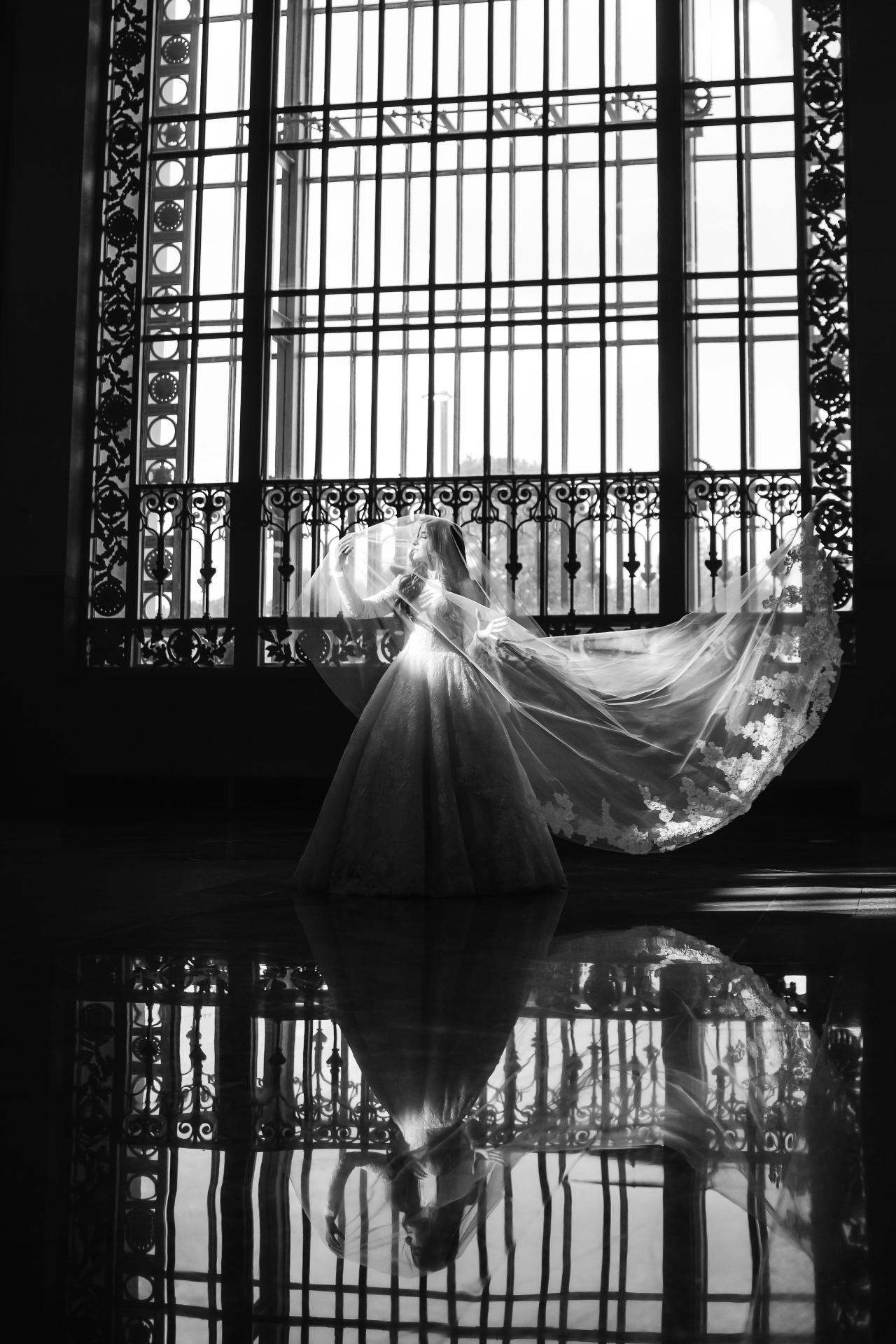 Black-and-white bride and veil reflected beneath an arched window. Jewish wedding in Detroit.
