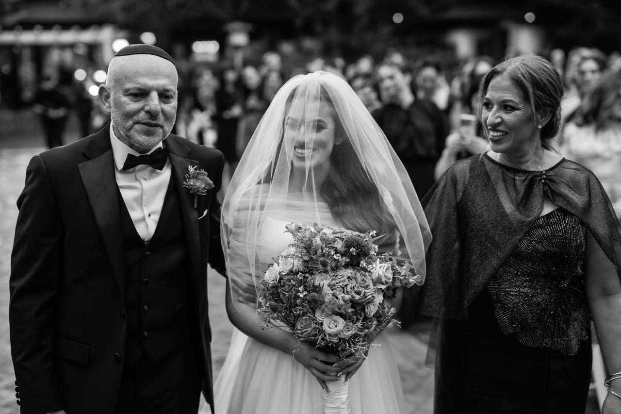 Bride approaching the chuppah with family. Crest Hollow wedding in Woodbury, Long Island.