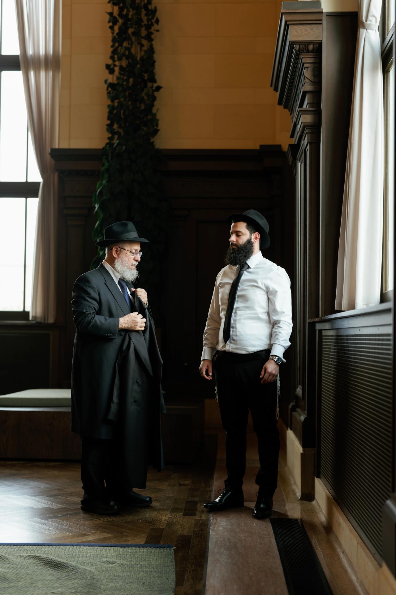 Groom receiving help with his wedding suit. Jewish wedding in Detroit.