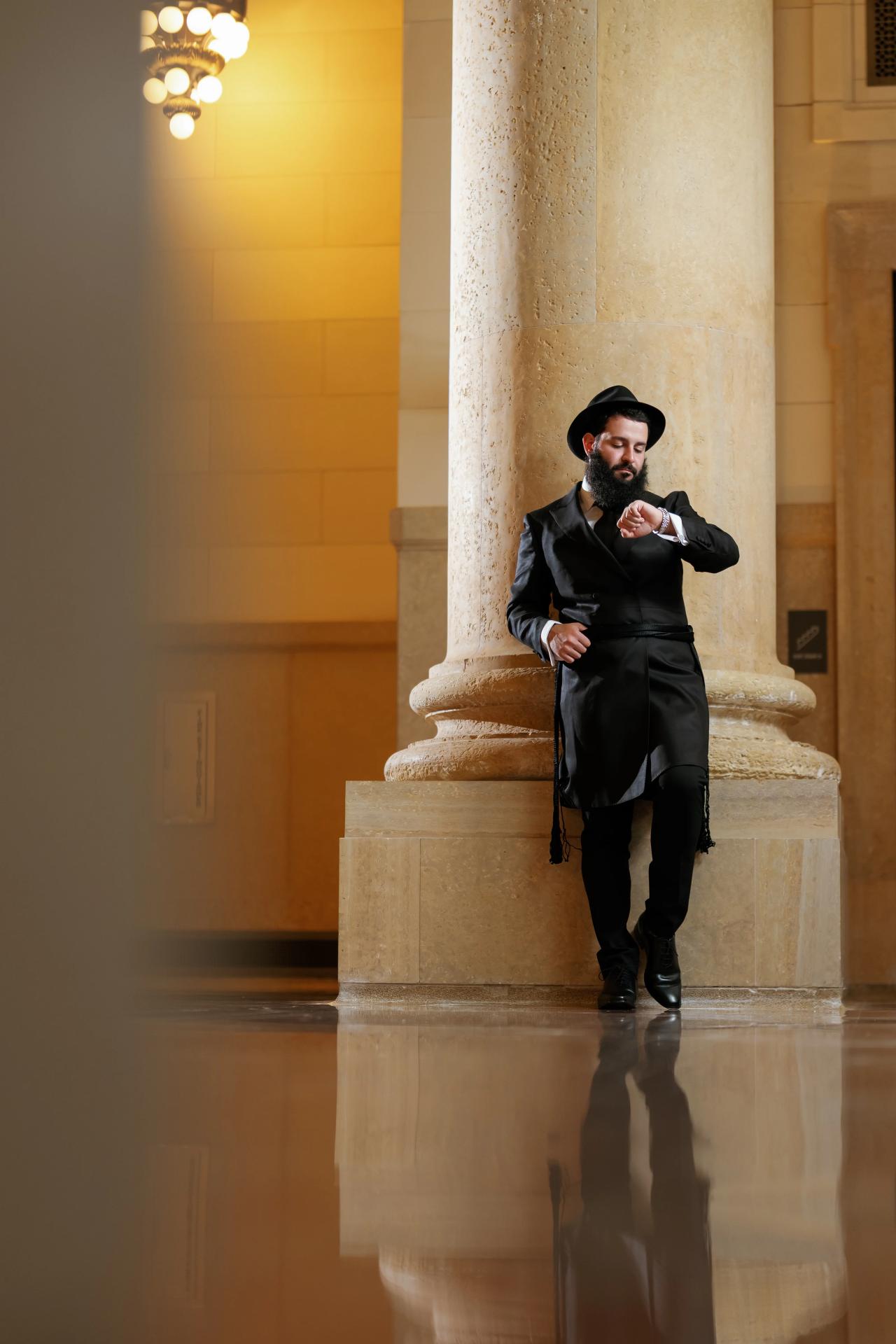 Groom framed by tall columns and polished-floor reflections. Jewish wedding in Detroit.